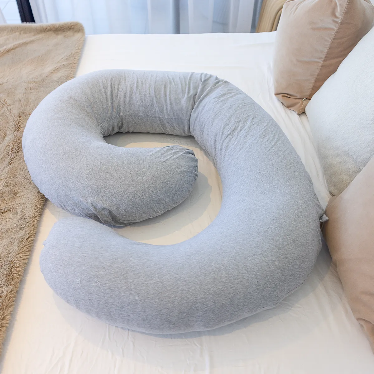 BodyCloud Pregnancy Pillow with grey cotton jersey cover curled up on a double bed